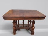 une vieille table en bois avec un plateau sculpté et des pieds tournés