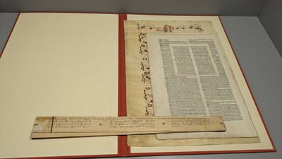un livre ouvert, avec une règle posée dessus, sur une table