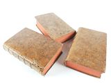 three old books sitting on top of each other on a white surface