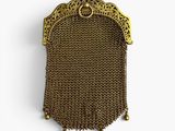 an antique gold chain purse hanging on a wall