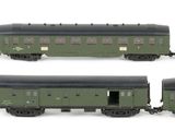 six green train cars are lined up on a white surface