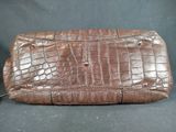 an image of a brown crocodile skin purse on a black background