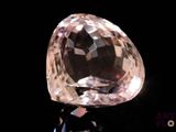 a pink diamond on a black surface with a black background