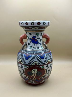 un vase avec un oiseau posé sur une table