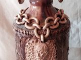 un vase marron orné de chaînes, posé sur une table