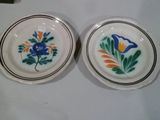 deux assiettes avec des fleurs et des feuilles peintes dessus, assises sur une table