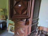 une armoire en bois dans un coin d'une pièce où se trouve un fauteuil à bascule