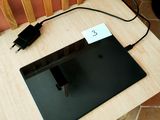 un ordinateur portable posé sur une table, avec un chargeur branché dessus