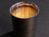 a close up of a metal cup on a black surface