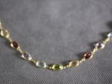a close up of a necklace with multi colored beads on a gray surface