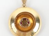 a close up of a gold locke with a red stone in the center