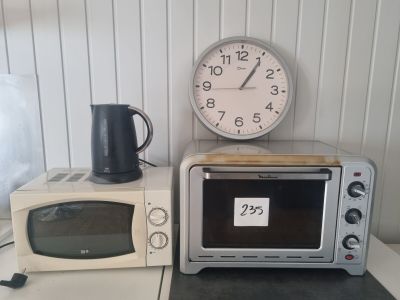 deux micro-ondes posés sur le plan de travail, avec une horloge accrochée au mur derrière eux