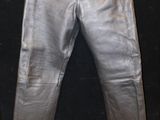 un pantalon en cuir argenté accroché à un mur noir