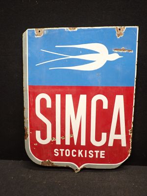 une enseigne indiquant « Concessionnaire Simca » sur laquelle figure un oiseau