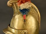 gold helmet with a feather on top of it on a stand