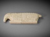 an image of a piece of carved ivory on a gray surface