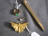 a gold pen, a ring, a butterfly, and a pen on a table