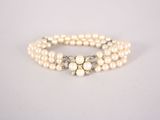 a close up of a bracelet with pearls on a white surface