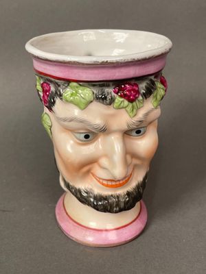 a ceramic cup with a man ' s face painted on it