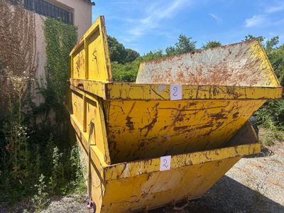 une benne jaune posée dans la terre