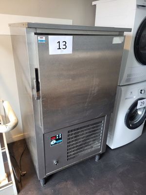 un réfrigérateur argenté à côté d'un lave-linge et d'un sèche-linge dans une pièce