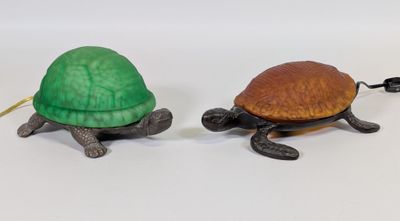 deux figurines de tortues assises l'une à côté de l'autre sur une surface blanche
