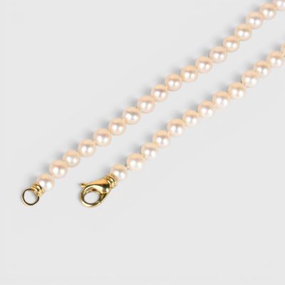 Gros plan sur un collier de perles blanches avec un fermoir en or