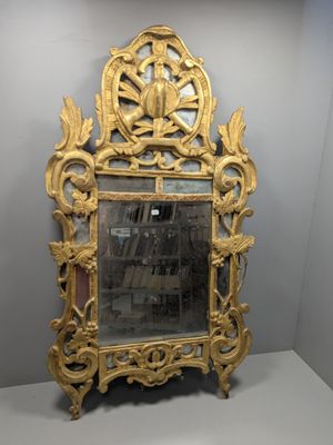 une image représentant un miroir à cadre doré posé sur une surface blanche