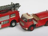 trois camions de pompiers miniatures et une voiture posés sur une surface blanche