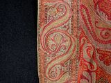 a close up of a red and gold paisley scarf
