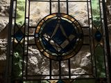 a stained glass window in the corner of a stone wall