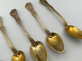 six antique spoons are lined up on a table next to a book
