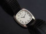 a silver watch with roman numerals on a black surface
