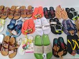 many pairs of sandals on a table next to a pair of flip flops