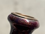 a purple vase with a gold rim sitting on a table