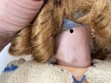 a hand holding a doll that has a haircut on it