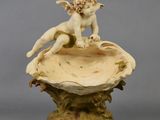 une image représentant la statue d'un garçon assis sur un coquillage