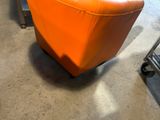 an orange chair that is sitting in the middle of a room
