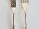 two forks and a knife on a white table