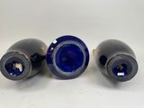 three blue vases sitting next to each other on a white surface