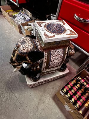 une statue d'éléphant posée par terre à côté d'une boîte de cigares