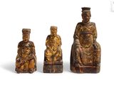 trois figurines sculptées représentant des personnes assises sur une chaise