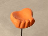 a close up of an orange plastic flower on a stick