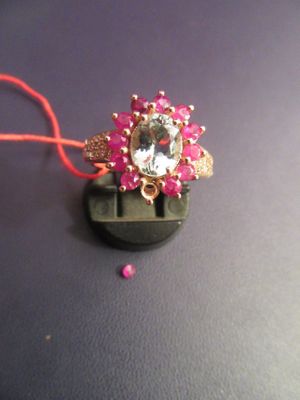 une perle rose et un anneau doré sur un fond noir