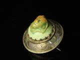 a close up of a ring with a green face on it
