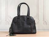 a black purse sitting on top of a wooden table next to a wall