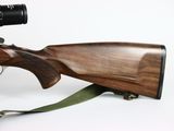 the rifle is sitting on a sling with a scope on it ' s side