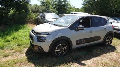 une voiture blanche garée dans un champ, avec d'autres voitures en arrière-plan