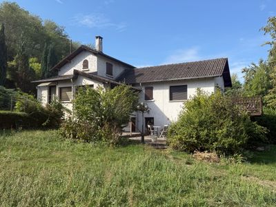 the house is in the middle of a grassy field with trees