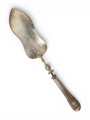 une cuillère en argent avec un manche en métal posée sur une surface blanche